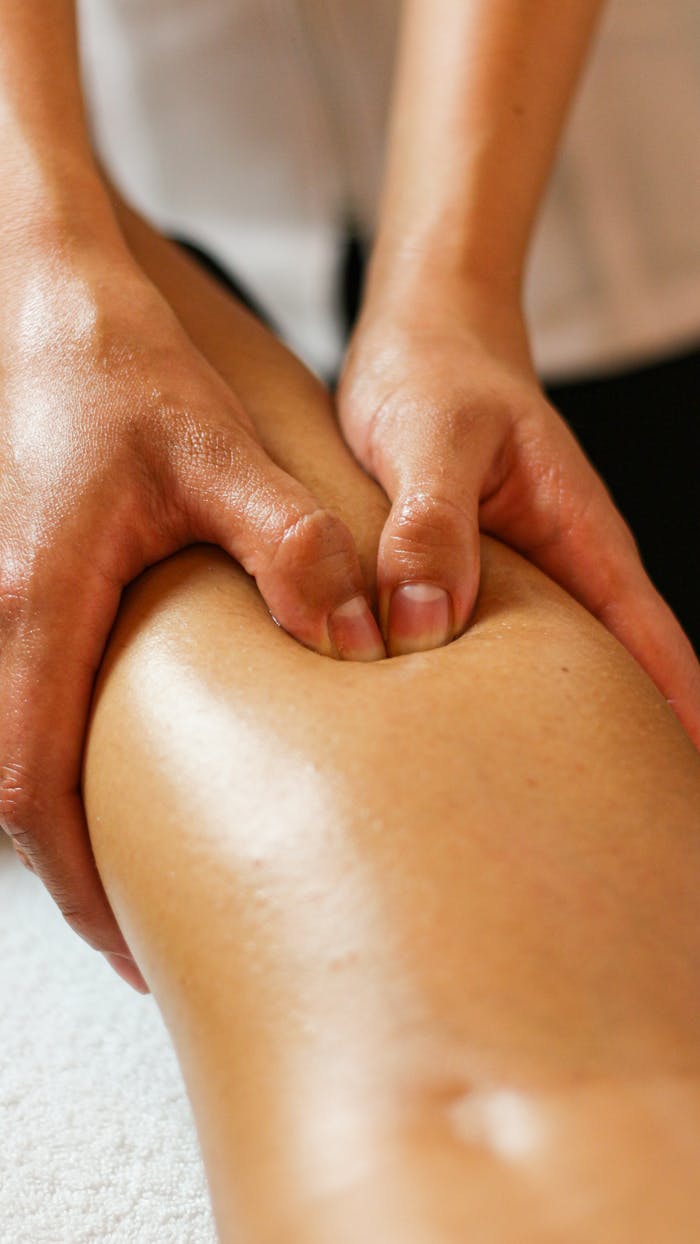 services-02 Close-up of hands applying pressure on a leg during a therapeutic massage session.